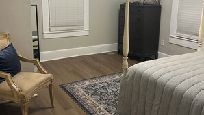 Un dormitorio con cama, una silla, cómoda y ventilador de techo.