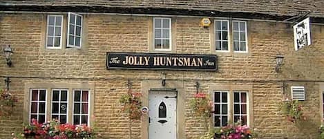 A stone building with a sign reading 'The Jolly Huntsman Inn.'