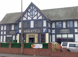 Um edifício tradicional com uma placa indicando 'HARLEY'S' e serviços de alimentação.