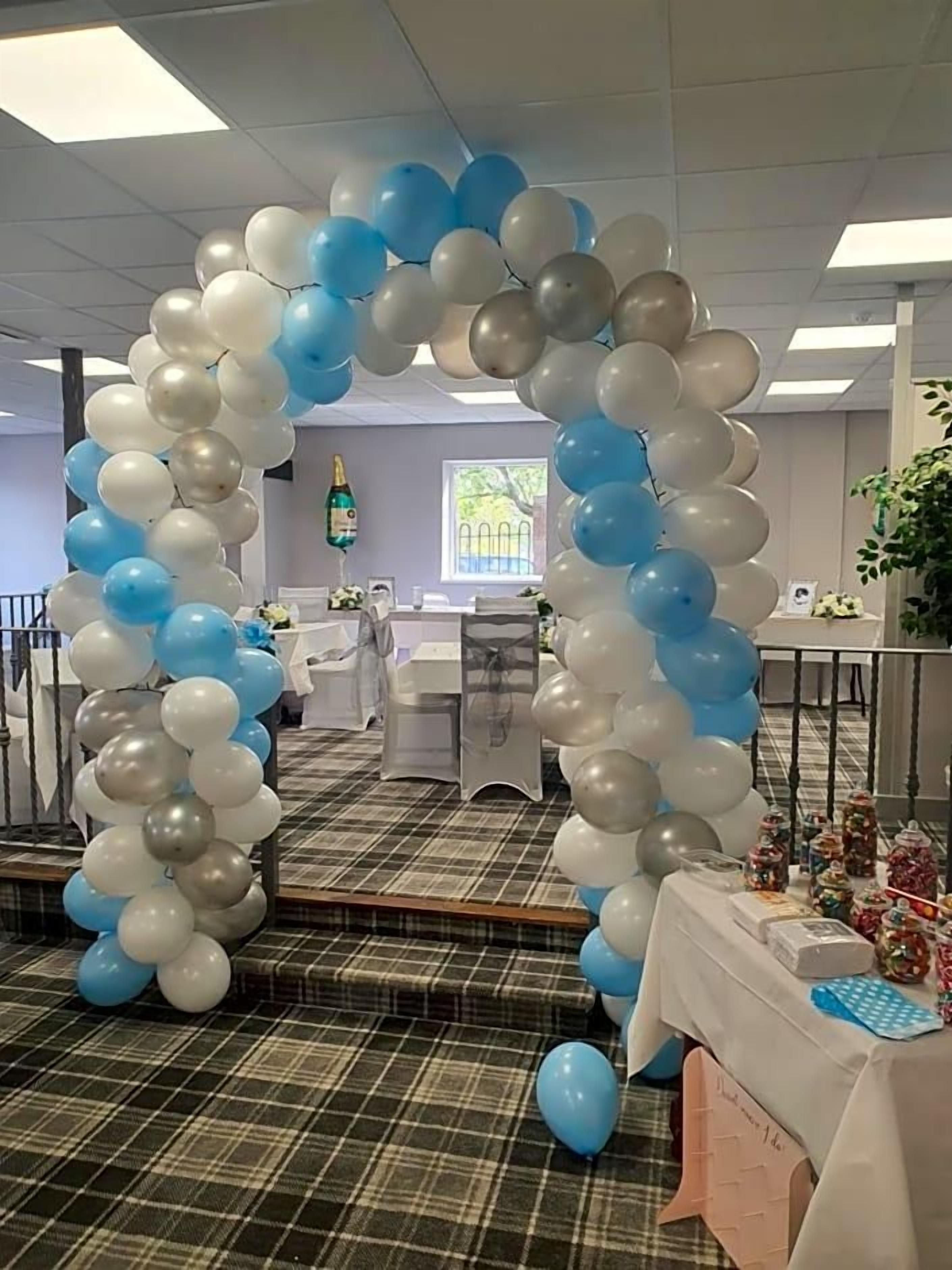A room with a checkered floor, a table with a white tablecloth, and a balloon archway.