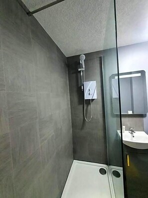 Un baño moderno con cabina de ducha de vidrio, lavabo blanco y espejo.