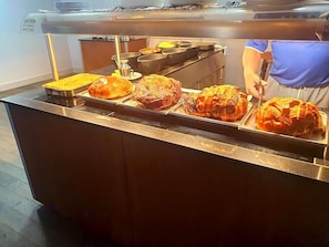 Ein Buffet mit verschiedenen Speisen, darunter ein großes Brathähnchen und andere zubereitete Gerichte.