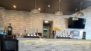 A bar area with a stone wall, hanging pendant lights, and a flat-screen TV mounted above the bar. - Harleys Inn (Chesterfield)