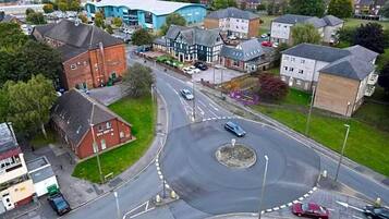 A roundabout with multiple entry and exit points, surrounded by residential buildings and a large industrial facility.
