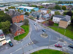 A roundabout with multiple entry and exit points, surrounded by residential buildings and a large industrial facility. - Harleys Inn (Chesterfield)