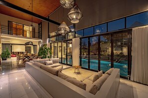 A spacious living area with a large sectional sofa, a dining table, and a pool view. - Villa Babar Pererenan (Pererenan)