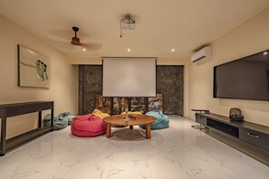 A modern living room with a flat-screen TV, a ceiling fan, a stone wall, and a marble floor. - Villa Babar Pererenan (Pererenan)