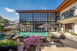 A modern house with a swimming pool, outdoor seating, and a large glass facade. - Villa Babar Pererenan (Pererenan)