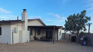 Un immobile residenziale con patio coperto, camino e vialetto in ghiaia.