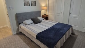 Una camera da letto con un letto, una ventola a soffitto, un comodino e una porta.
