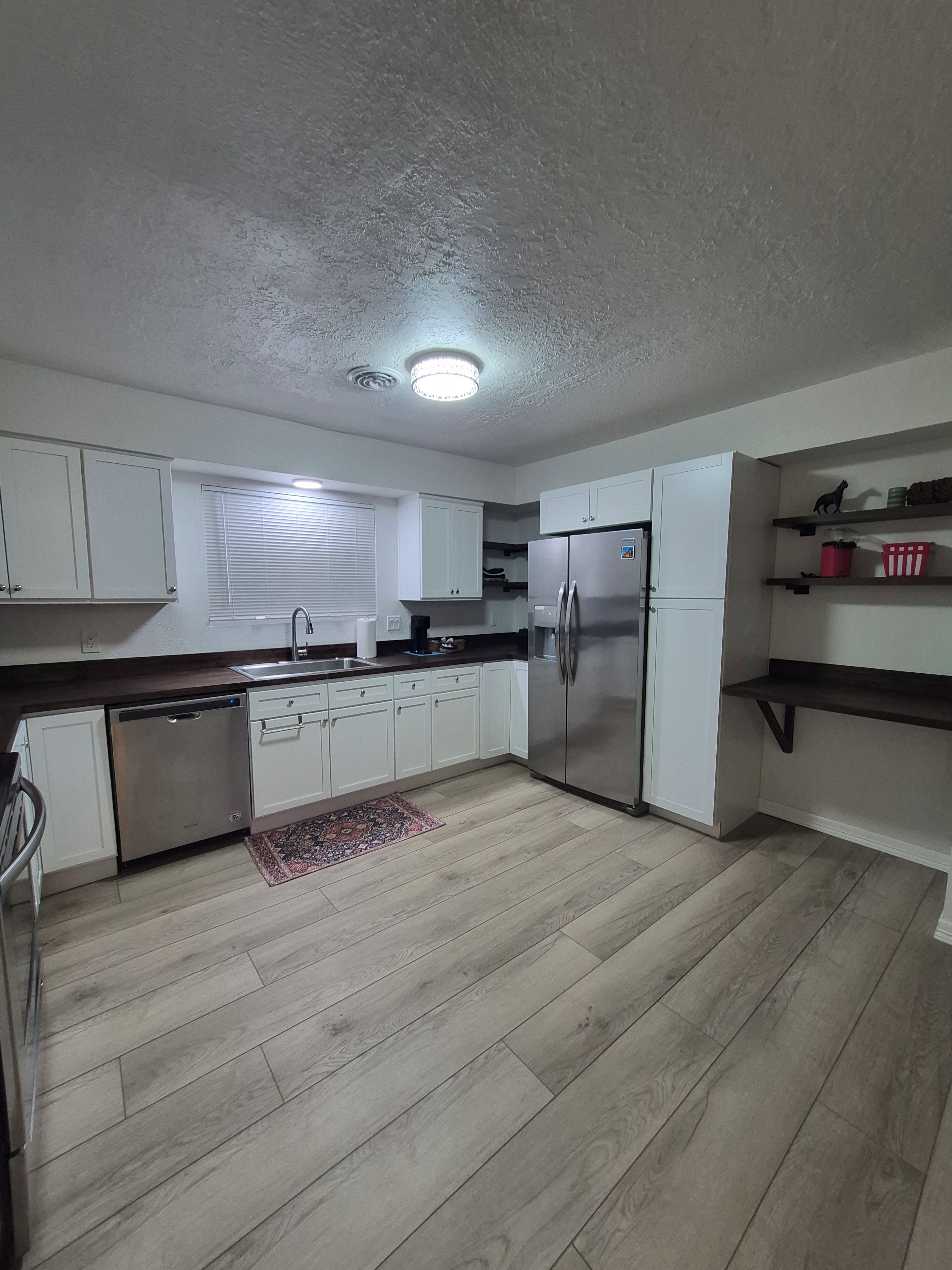 Una cocina moderna con armarios blancos, un refrigerador de acero inoxidable y un lavavajillas.