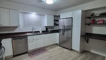 Una cocina moderna con armarios blancos, un refrigerador de acero inoxidable y un lavavajillas.
