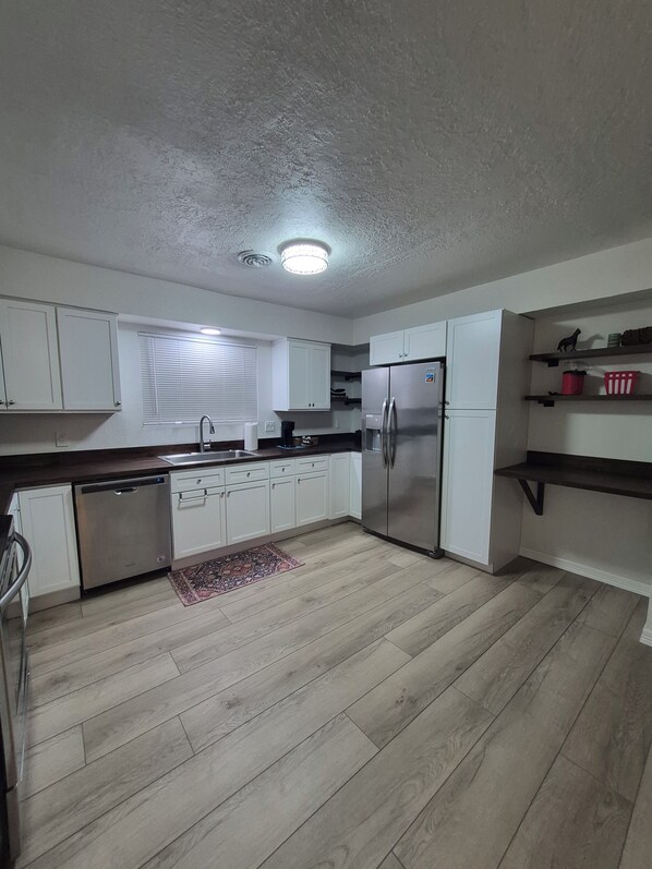 A modern kitchen with white cabinets, a stainless steel refrigerator, and a dishwasher.