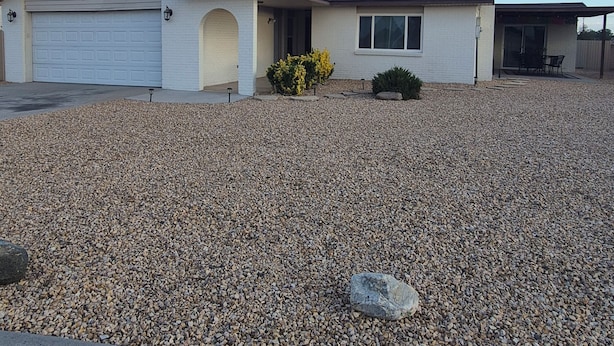 Una casa residenziale con garage, patio coperto e vialetto in ghiaia.