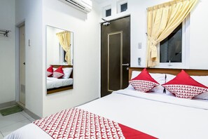 Una habitación de hotel con una cama, un armario, un espejo y una ventana con cortinas.