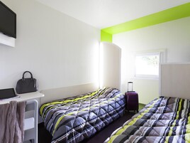 Habitación de hotel con dos camas, un escritorio, una computadora portátil, una maleta y una ventana.