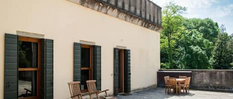Um edifício com três janelas e um pátio com mobiliário de exterior.