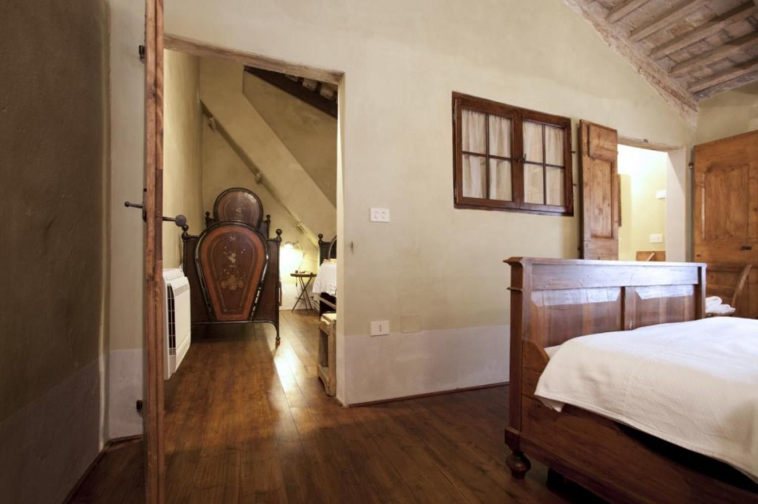 Un dormitorio con cama y armario de madera, y una escalera que lleva a otra habitación.