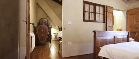 Un dormitorio con cama y armario de madera, y una escalera que lleva a otra habitación.