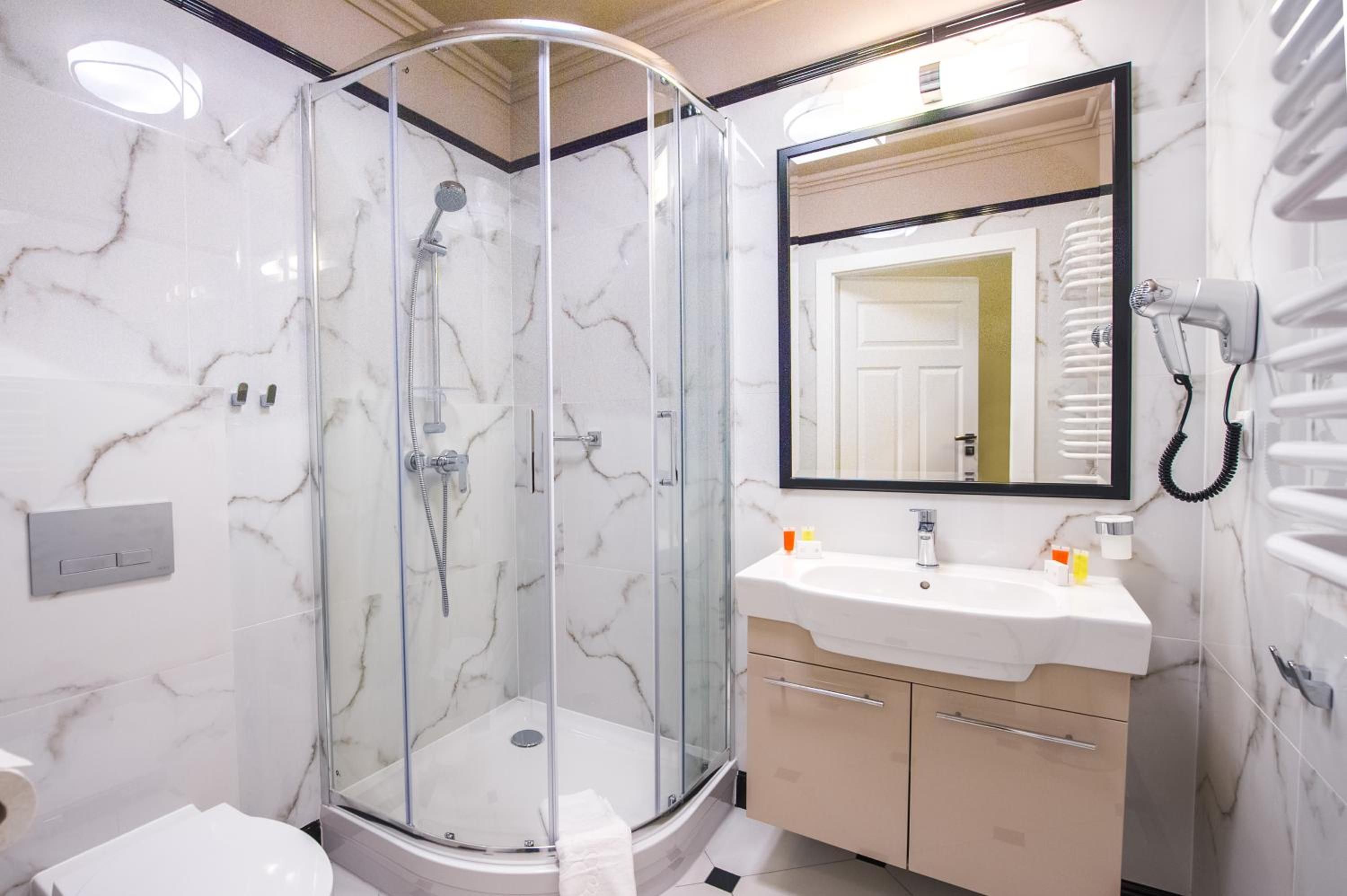Ein modernes Badezimmer mit einer gläsernen Dusche, einem Waschbecken inklusive Spiegel und einem Handtuchhalter.