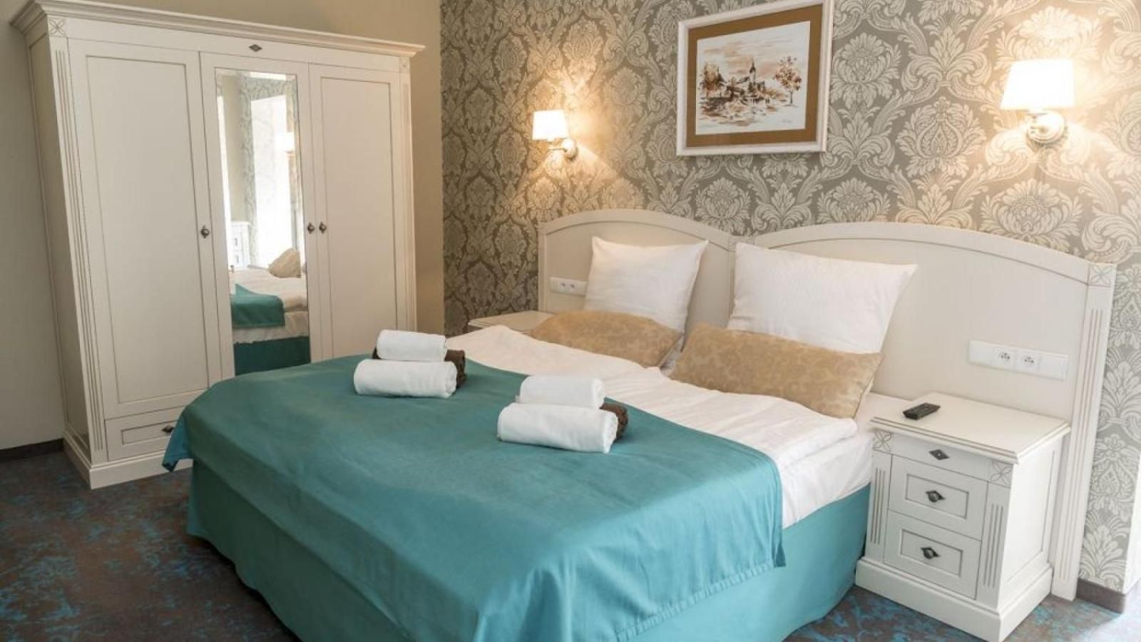 Habitación de hotel con cama, mesita de noche, armario y un cuadro en la pared.