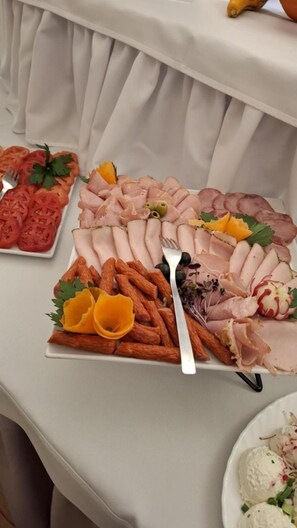 Una mesa de bufé con diversos alimentos, como carnes en rodajas, verduras y guarniciones.