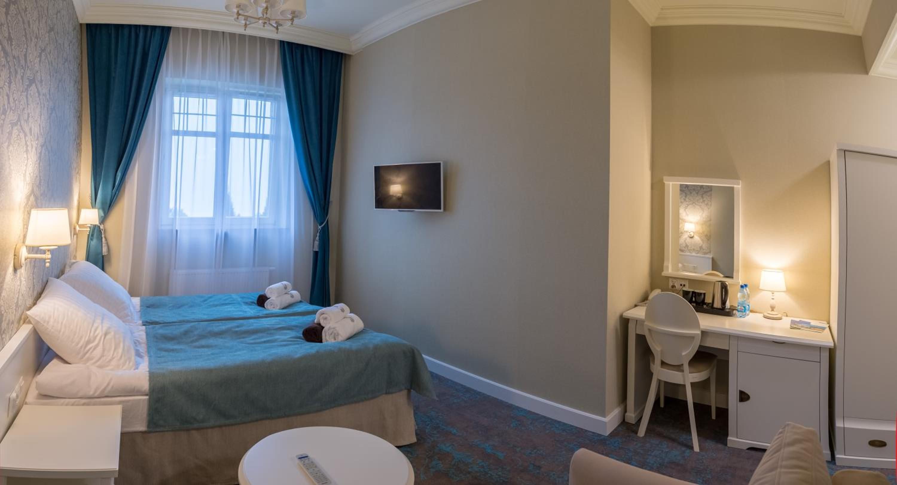 Ein Hotelzimmer mit Bett, Schreibtisch, Stuhl, Fernseher und Spiegel.