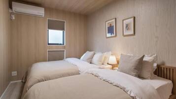 A bedroom with two beds, an air conditioning unit, a window, and a wall-mounted picture.