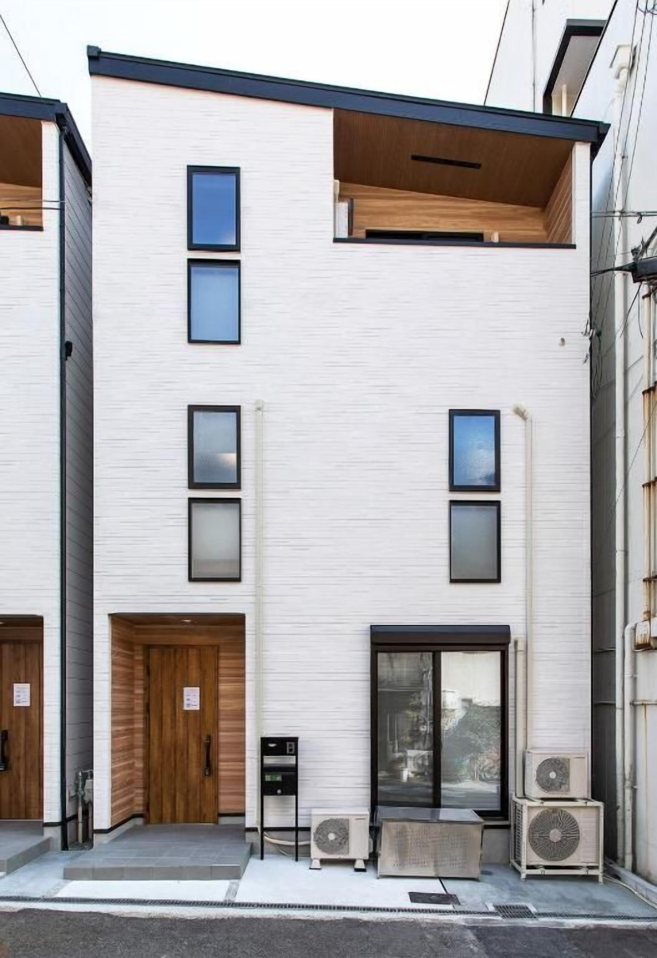 A modern two-story building with a flat facade, large windows, and a wooden door.