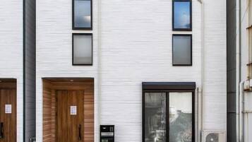 A modern two-story building with a flat facade, large windows, and a wooden door.