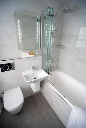 Uma casa de banho moderna com chuveiro em cabine de vidro, lavatório branco e sanita.