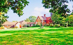 A residential property with a large lawn, a brick house, and a smaller building. - Oldlands Farm Bed and Breakfast (Crawley)