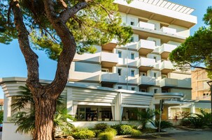 Un hotel a più piani con un design architettonico moderno, caratterizzato da balconi su ogni piano e un ingresso centrale con portico.