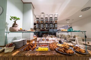 Un bufé con diversas opciones de comida, incluyendo pastelería y una estación de café.