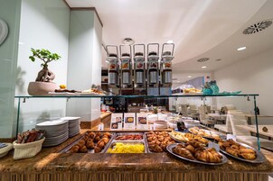 Un buffet con diverse opzioni gastronomiche, tra cui pasticcini e una postazione caffè.