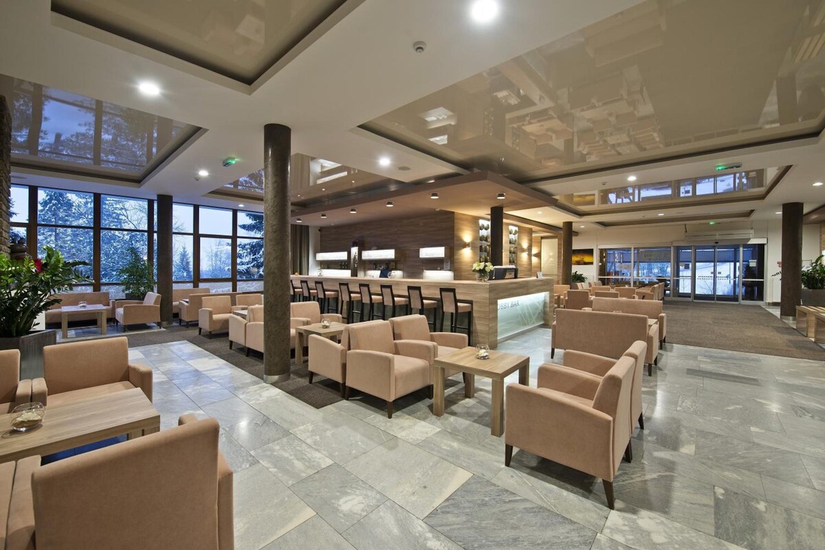 Un'ampia hall con diverse zone relax, una reception e grandi finestre con vista sull'esterno.