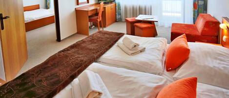 A hotel room with two beds, a desk, a television, and a window with curtains.