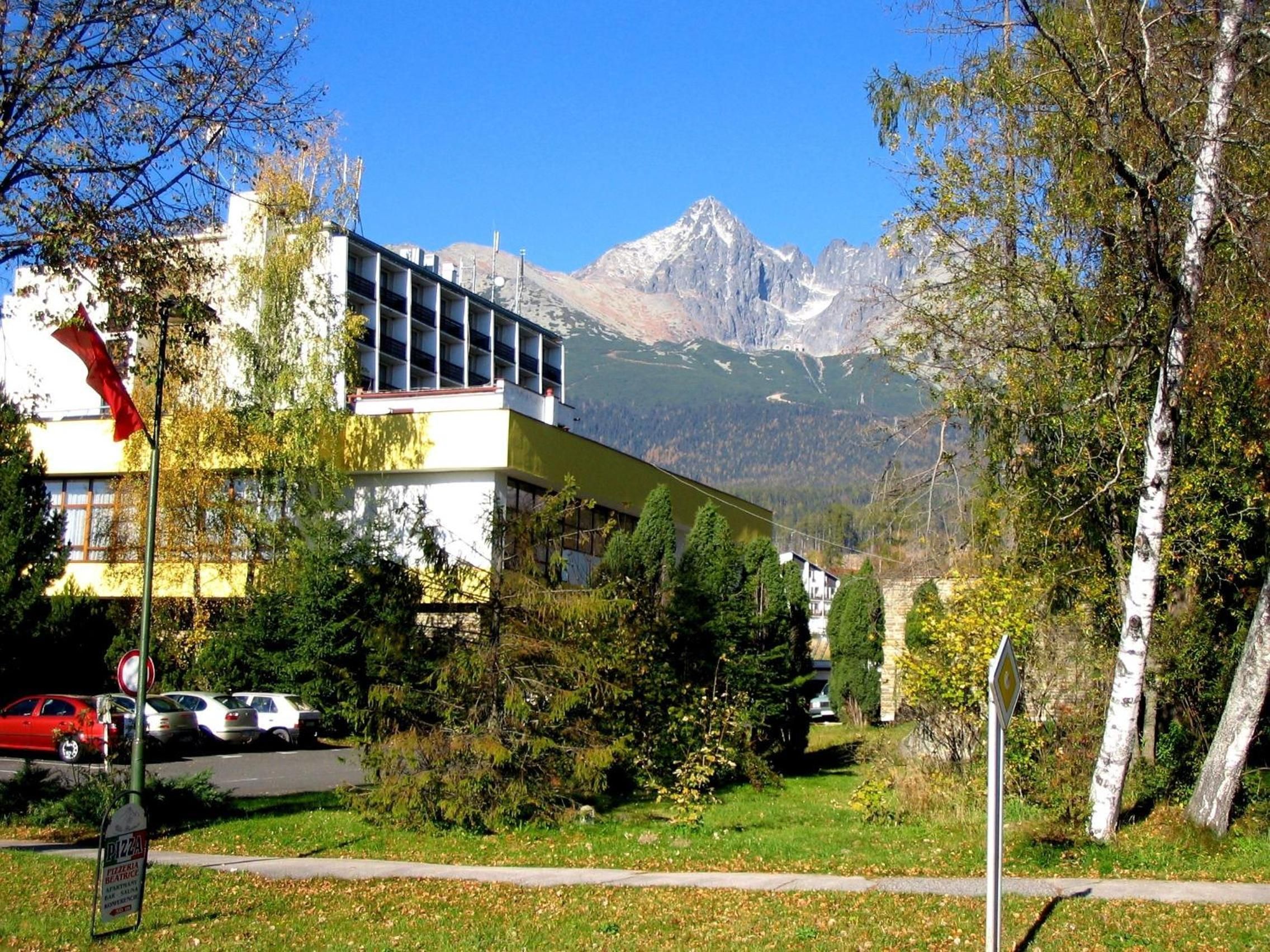 A building with a modern design, a parking area, and a mountain view in the background.