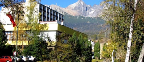 A building with a modern design, a parking area, and a mountain view in the background.
