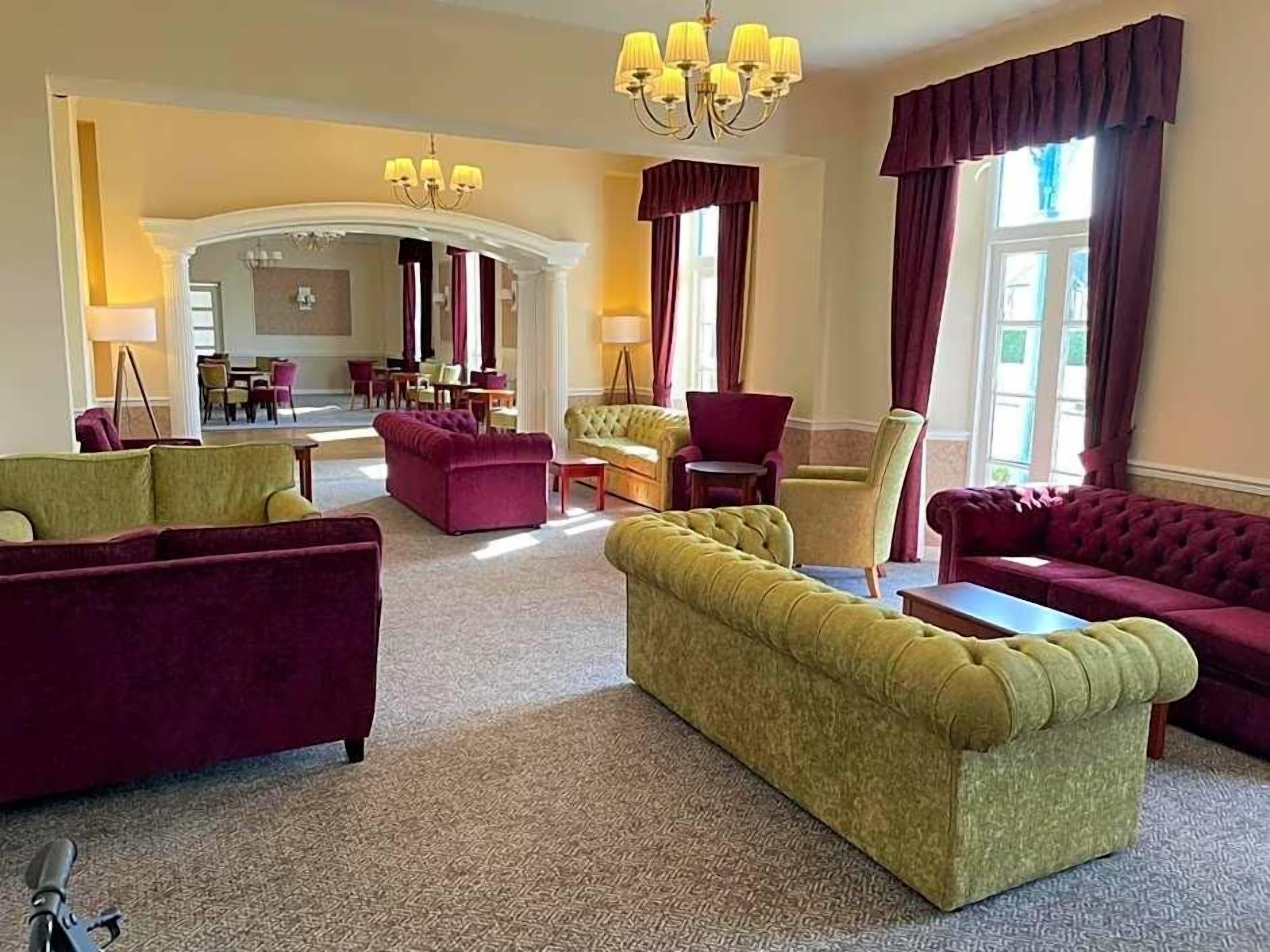 Ein großzügiger Loungebereich mit verschiedenen Sitzgelegenheiten, darunter Sofas und Sessel, die um einen zentralen Couchtisch angeordnet sind.