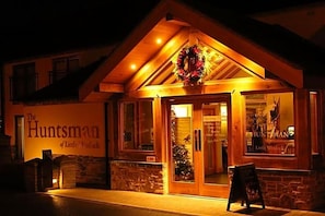 A building with a sign reading 'The Huntsman of Little Wenlock' and a wreath on the entrance.