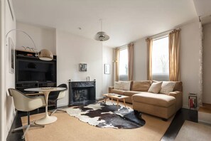 A living room with a sofa, a coffee table, a fireplace, and a television.