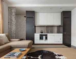 A modern living room with a sofa, a coffee table with a book and a plate, and a cowhide rug.