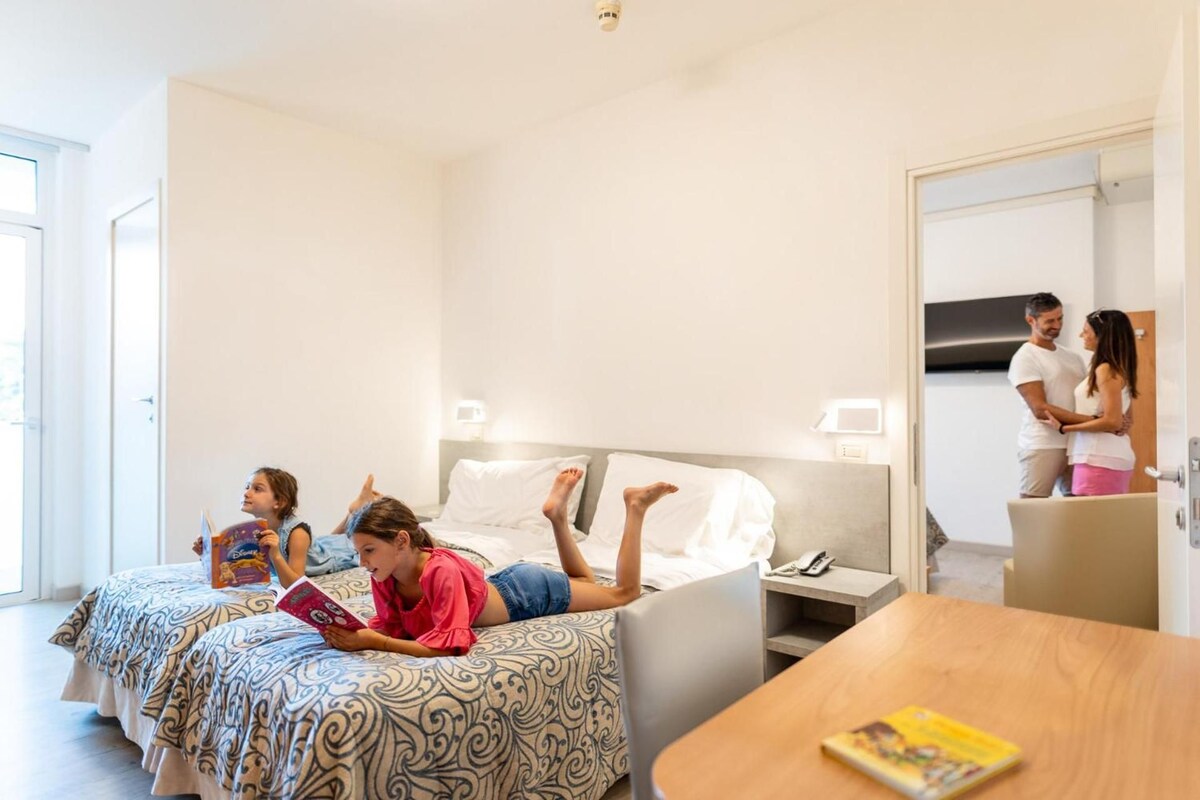 Una habitación de hotel con una cama, mesita de noche y un espejo.