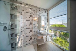 Un baño moderno con cabina de ducha de vidrio, un ventanal y vistas al exterior.