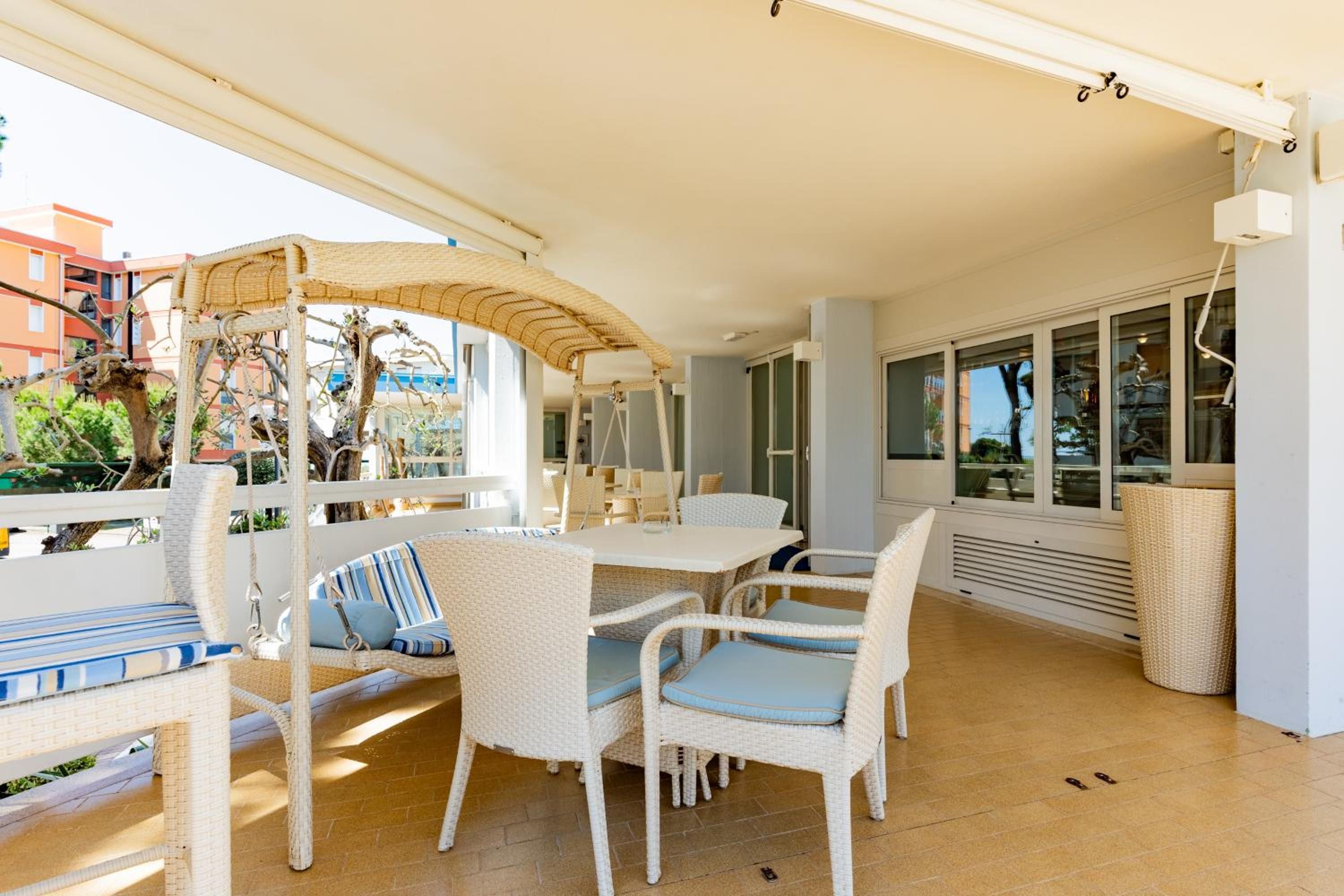 A covered outdoor seating area with wicker furniture and a table.