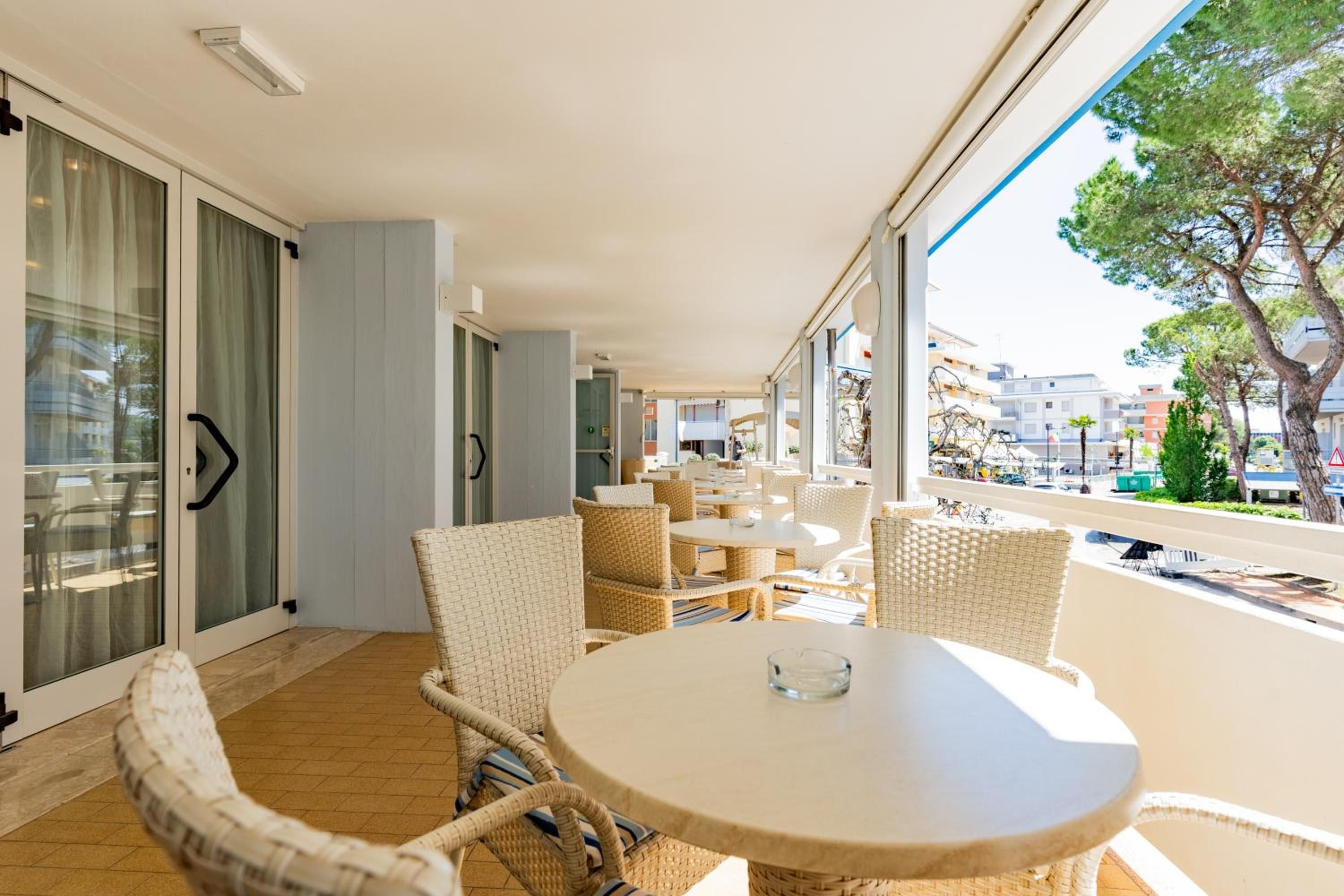 A balcony with wicker furniture and a glass door leading to a room.