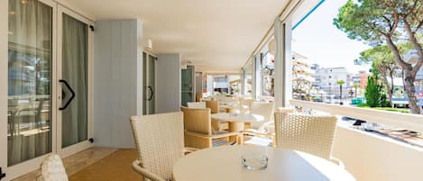 A balcony with wicker furniture and a glass door leading to a room.