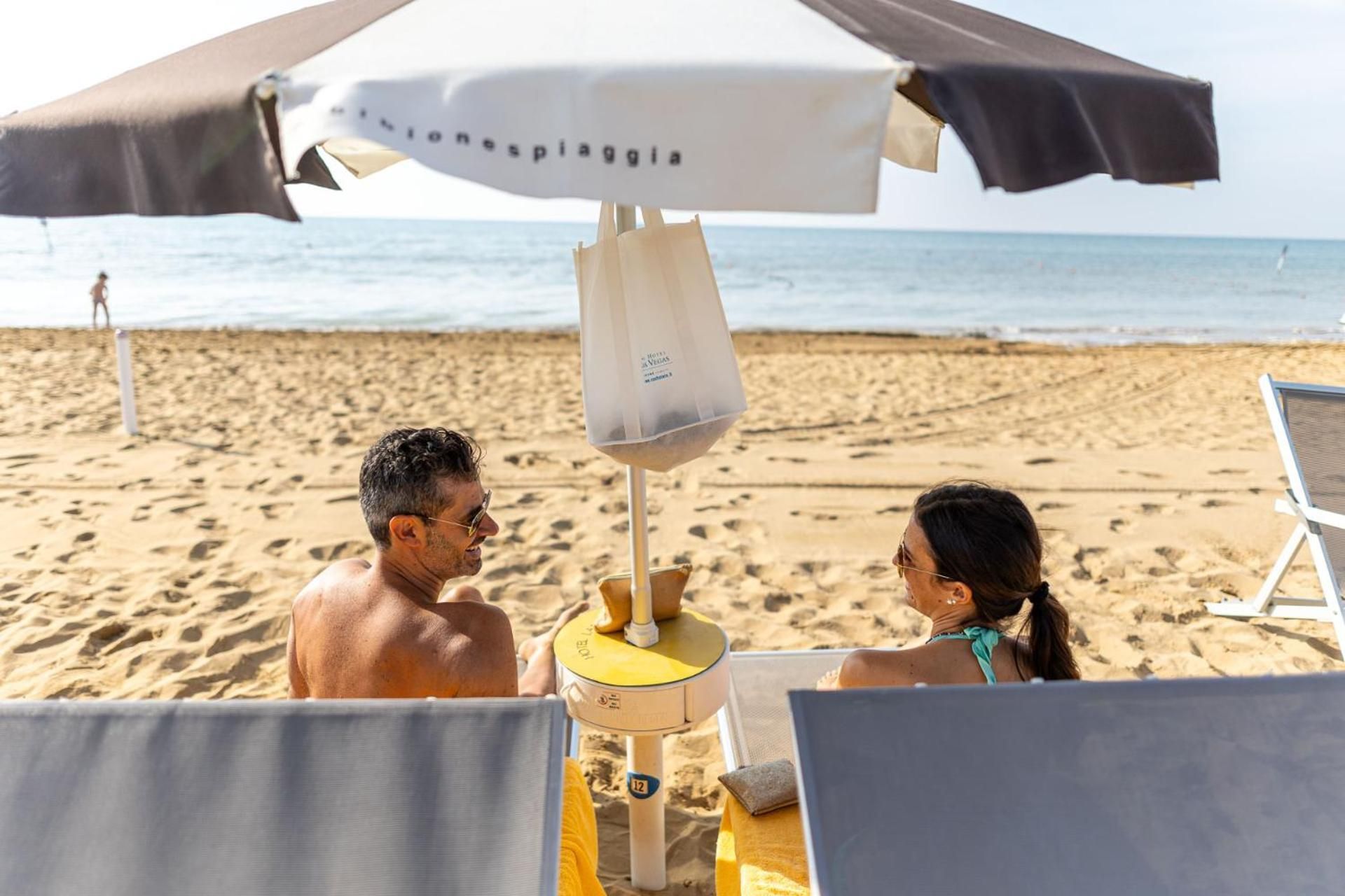 Cena de praia com guarda-sol, cadeira de praia e espreguiçadeira.