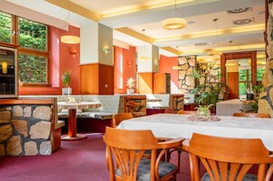A restaurant with a stone wall, wooden furniture, and large windows.
